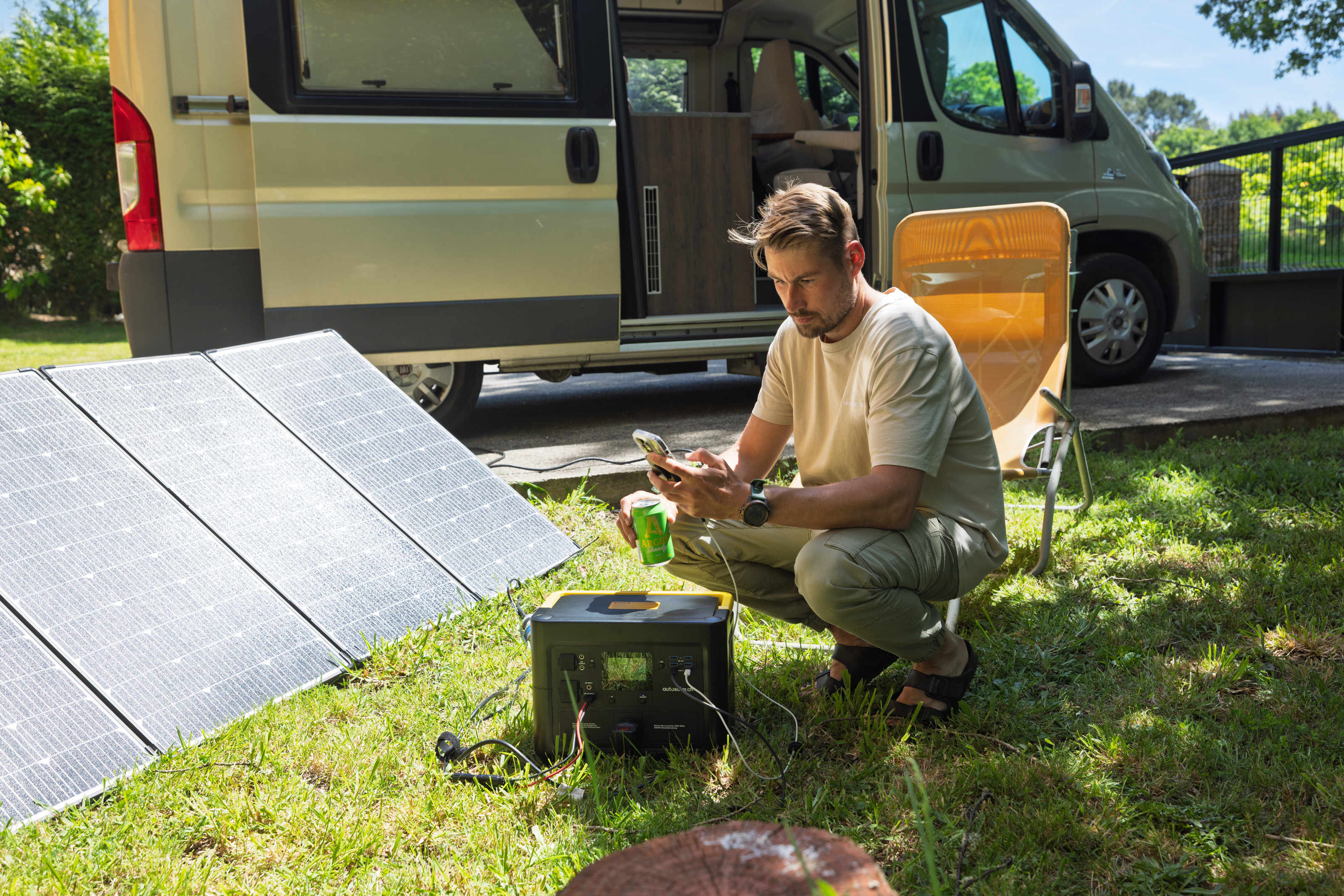 Mann beim Camping vor seinem Van, lädt sein Smartphone an einer Powerstation, die über Solarpanels betrieben wird – eine der 5 besten Solaranlagen für unterwegs